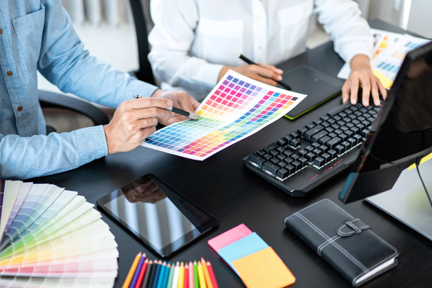 187665069_m (1) (1) Team graphic designer working on document of color chart to brainstorming about new project and using laptop to working graphic together in office<br />