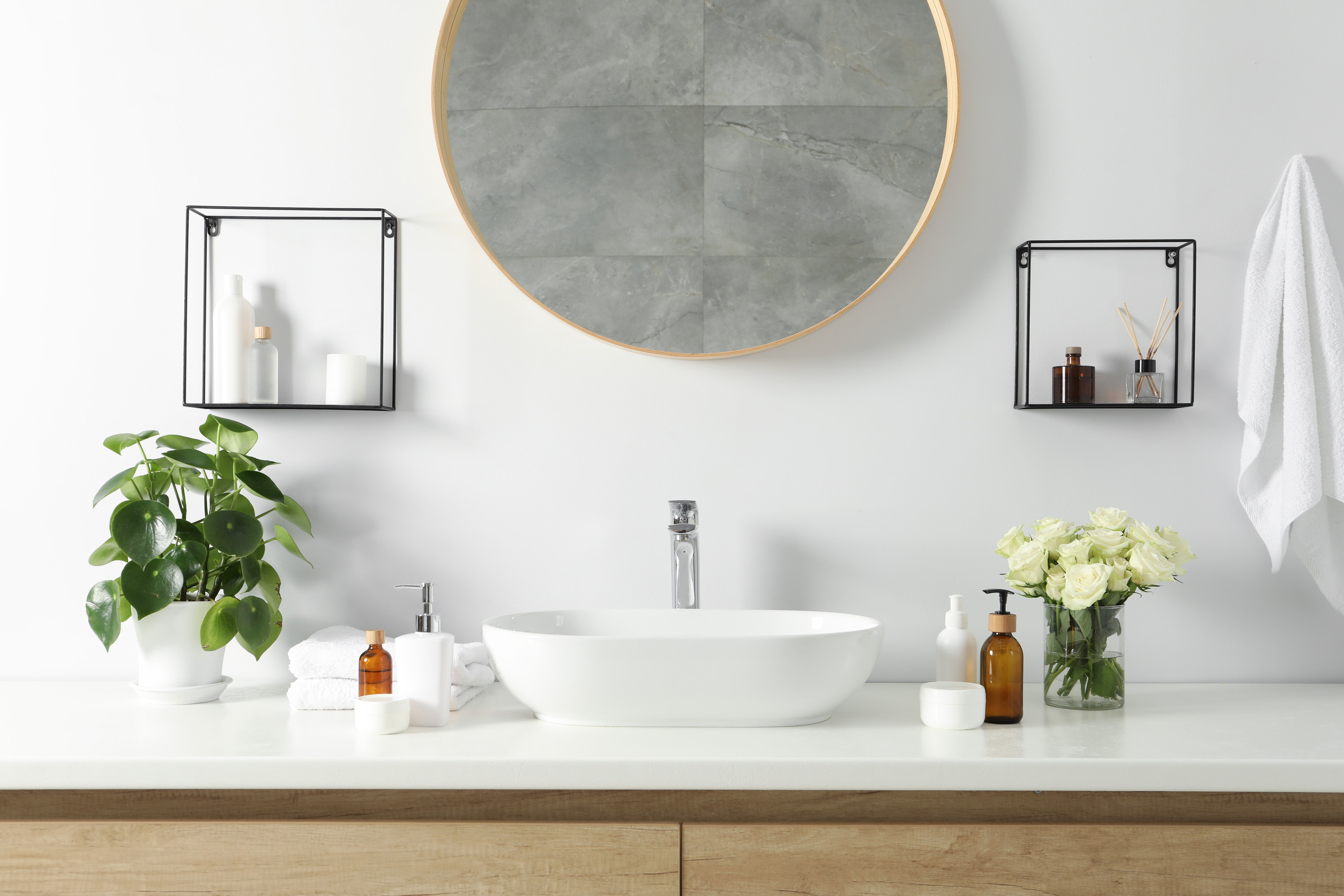 Beautiful roses, houseplant and bath accessories near sink in ba Beautiful roses, houseplant and bath accessories near sink in bathroom