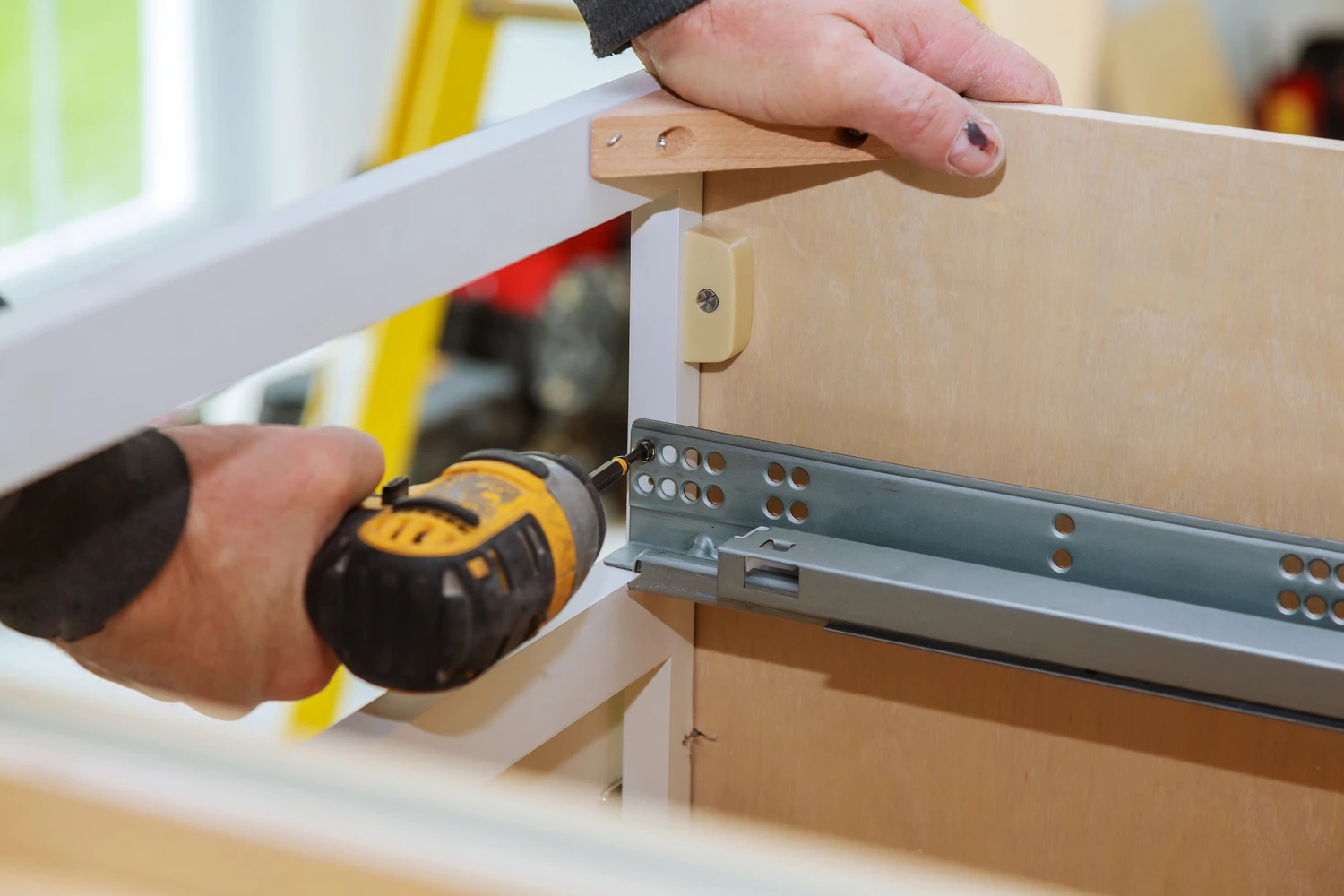 A workman fixing cabinet with screwdriver in kitchen kitchen cabinets<br />
